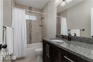 Full bathroom featuring vanity, toilet, shower / bath combo with shower curtain, and tile floors