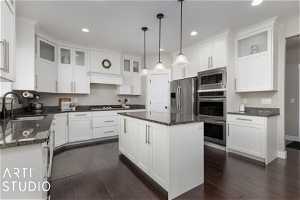Kitchen with a center island, dark wood flooring, sink, pendant lighting, and appliances with stainless steel finishes