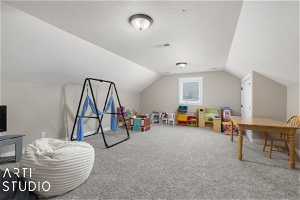 Rec room featuring light colored carpet, a textured, lofted ceiling