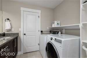 Laundry room with light tile flooring, double sinks, hookup for a washing machine, and washing machine and clothes dryer