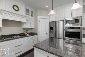 Kitchen with pendant lighting, white cabinetry, and appliances with stainless steel finishes
