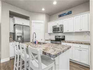 Kitchen featuring dark hardwood / wood-style floors, appliances with stainless steel finishes, and backsplash