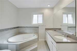 Primary Bathroom with a wealth of natural light, tile floors, double sink vanity, and a relaxing tiled bath