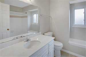 Main Bathroom featuring a wealth of natural light, oversized vanity, and toilet