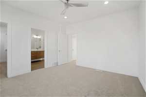 Unfurnished bedroom featuring ensuite bathroom, ceiling fan, and light colored carpet