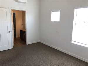 Unfurnished bedroom with dark colored carpet and connected bathroom