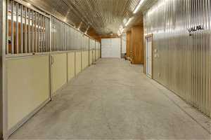 Barn interior with four stalls on the left, door to bathroom, two hay stalls, wash stall and tack room on the right