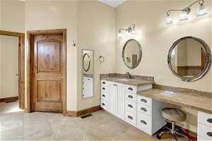 Master Bathroom with oversized vanity and tile flooring and door leading to closet