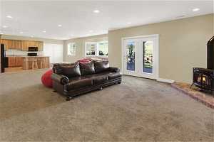 Basement Family room with kitchen featuring light colored carpet, a wood stove, and french doors