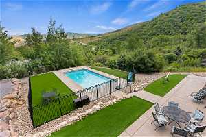 View of swimming pool with a patio, a mountain view, and a lawn