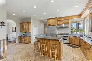 Kitchen with light tile floors, premium appliances, a center island, sink, and a breakfast bar