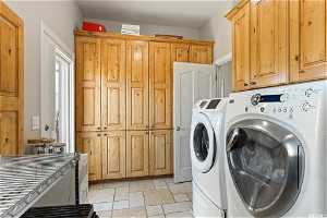 Laundry room with independent washer and dryer, light tile flooring, and cabinets