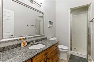 Bathroom with a shower with shower door, vanity with extensive cabinet space, toilet, and tile floors