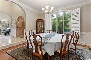 Dining space with an inviting chandelier, hardwood / wood-style floors, and crown molding