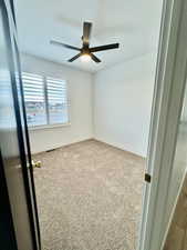 Empty room with light colored carpet and ceiling fan