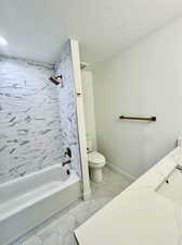 Full bathroom with vanity, tiled shower / bath, a textured ceiling, and toilet