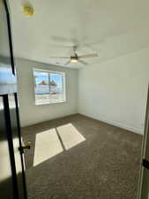 Unfurnished room with dark carpet, ceiling fan, and a textured ceiling