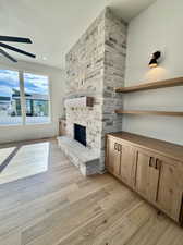 Unfurnished living room featuring ceiling fan, a fireplace, and light hardwood / wood-style floors