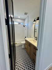 Full bathroom with a textured ceiling, tile patterned floors, vanity, tiled shower / bath, and toilet