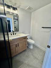 Bathroom with a textured ceiling, a shower, vanity, and toilet