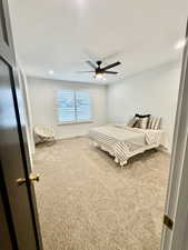 Carpeted bedroom with ceiling fan, a textured ceiling, and fridge