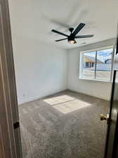 Spare room featuring a textured ceiling, carpet floors, and ceiling fan