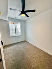 Spare room with ceiling fan, a textured ceiling, and carpet