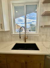 Kitchen with decorative backsplash, sink, and light stone counters