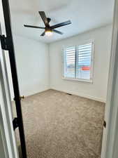 Carpeted empty room with ceiling fan and a textured ceiling