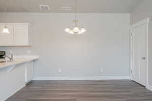 Unfurnished dining area with sink, an inviting chandelier, and hardwood / wood-style floors