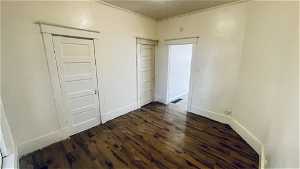 Empty room featuring crown molding and dark wood-type flooring