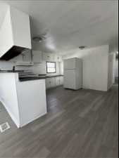 Kitchen featuring white cabinets, white refrigerator, range, and dark wood-type flooring