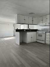 Kitchen with light wood-type flooring, white range, and white cabinets