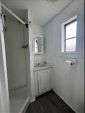 Bathroom with hardwood / wood-style floors, a shower, and vanity