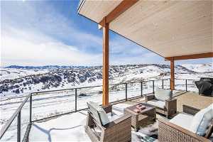 Snow covered back of property featuring an outdoor living space and a mountain view