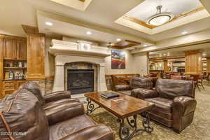 Living room featuring a tiled fireplace, a tray ceiling, crown molding, and carpet