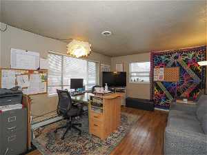 Office space featuring baseboard heating, dark hardwood / wood-style flooring, and a textured ceiling