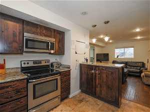 Kitchen with light hardwood / wood-style floors, appliances with stainless steel finishes, and dark brown cabinets