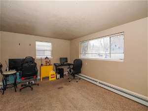 Office area featuring plenty of natural light, carpet floors, a baseboard radiator, and a textured ceiling
