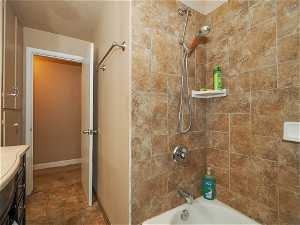 Bathroom with vanity, tiled shower / bath combo, tile floors, and a textured ceiling