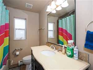 Bathroom featuring a baseboard radiator, a textured ceiling, toilet, tile flooring, and vanity with extensive cabinet space