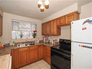 Kitchen featuring a notable chandelier, light tile flooring, electric stove, sink, and white refrigerator