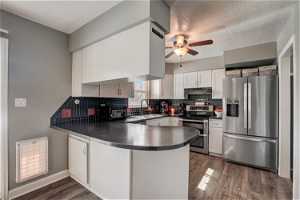 Kitchen featuring dark hardwood / wood-style flooring, stainless steel appliances, and white cabinetry