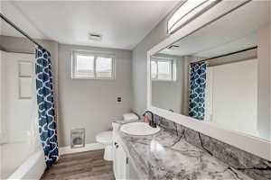 Full bathroom with vanity, toilet, hardwood / wood-style floors, and shower / bath combo with shower curtain