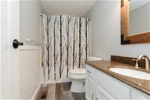Bathroom with toilet, tile walls, hardwood / wood-style flooring, and oversized vanity
