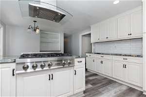 Kitchen featuring dark hardwood / wood-style floors, stainless steel gas cooktop, dark stone counters, and white cabinets