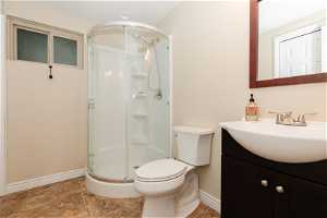 Bathroom featuring vanity, toilet, an enclosed shower, and tile floors