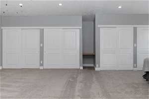 Unfurnished bedroom featuring two closets, light colored carpet, and a textured ceiling