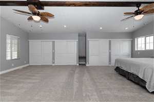 Unfurnished bedroom featuring light carpet, ceiling fan, and two closets