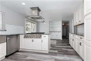 Kitchen featuring white cabinets, dark hardwood / wood-style flooring, island range hood, and backsplash